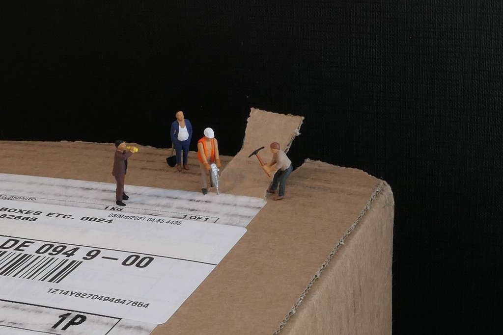 Miniature construction crew opening up a Formex Swiss watches delivery package